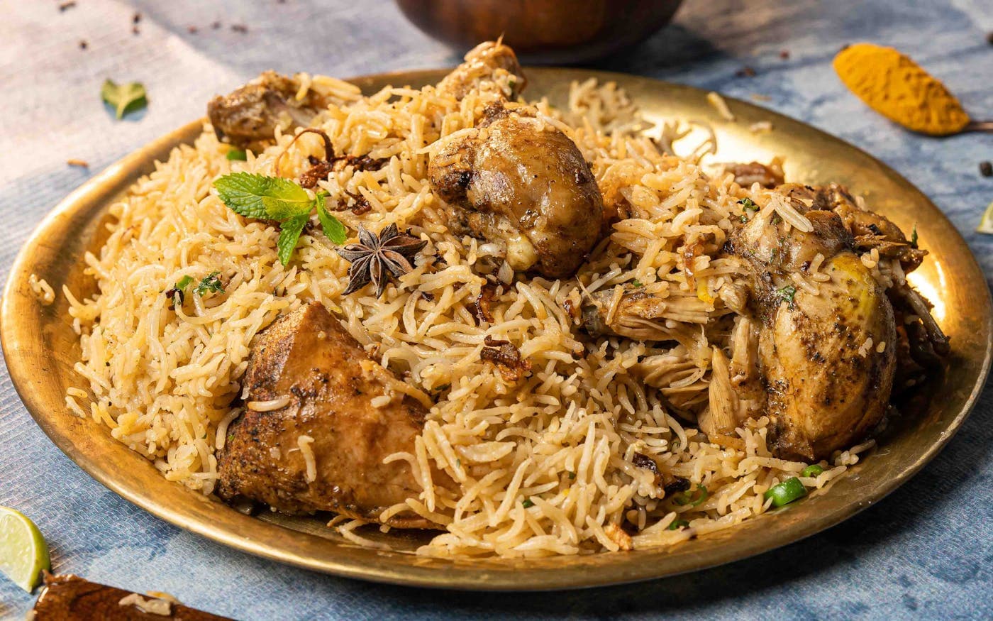 Chicken biryani served on a brass plate with whole spices
