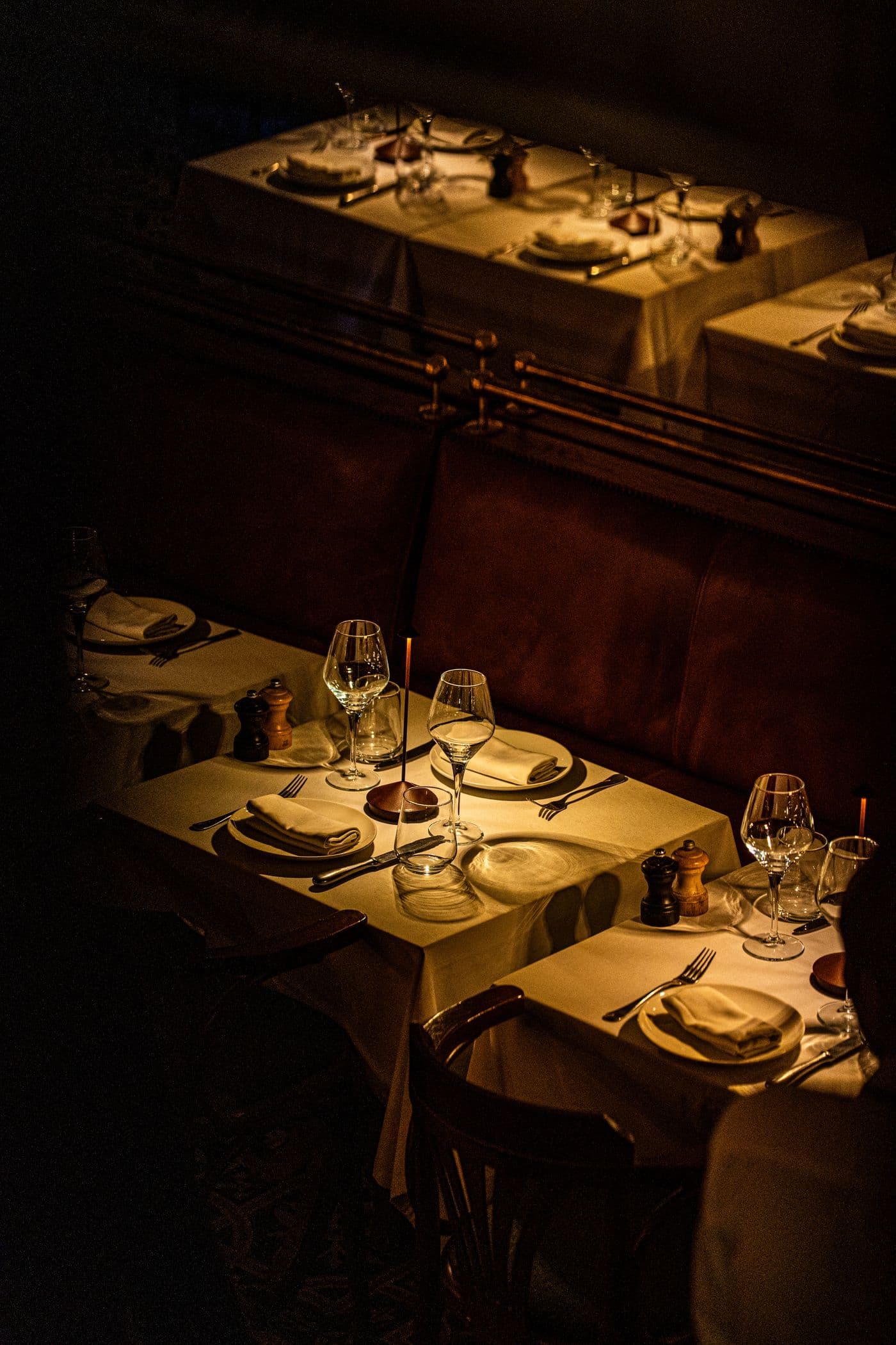 Warm, dim-lit dining room with candlelight and oxblood banquette seating